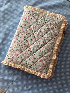 a blue and white quilted pillow with flowers on it sitting on a wooden table