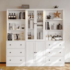 a white bookcase filled with lots of books on top of a hard wood floor