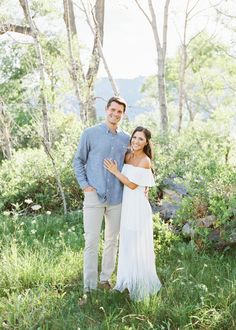 a man and woman standing in the grass with their arms around each other, smiling at the camera