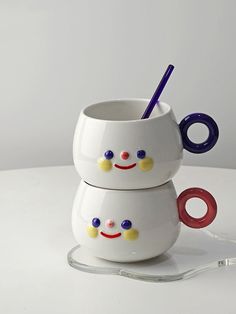 two white cups with colorful handles and faces on them