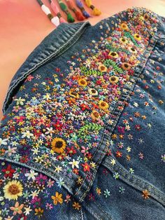 a pair of blue jean shorts with colorful flowers on them and crayons in the background