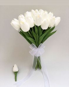 a bouquet of white tulips tied to a ribbon with a single flower on the side