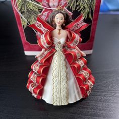 a red and white angel figurine sitting on top of a table next to a box