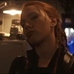 a woman with red hair and braids standing in a kitchen looking off to the side