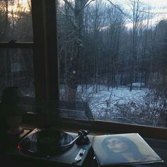 a record player sitting on top of a table in front of a window next to a forest