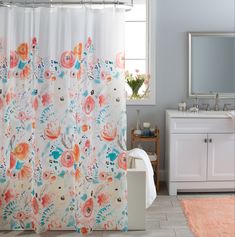 a bathroom with a floral shower curtain next to a sink