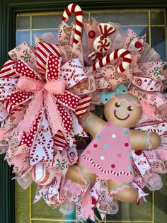 a christmas wreath with a teddy bear and candy canes hanging on the front door