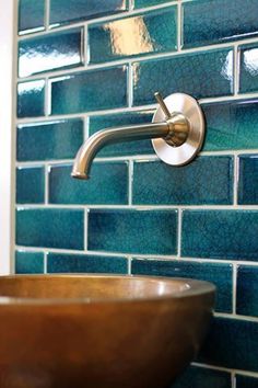 a bathroom sink sitting under a faucet next to a blue tiled wall