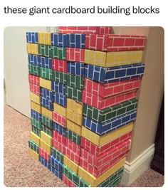 a stack of colorful blocks sitting on top of a floor next to a wall with text that reads, these giant cardboard building blocks