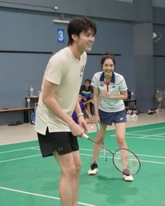 two people standing on a tennis court holding racquets and smiling at each other