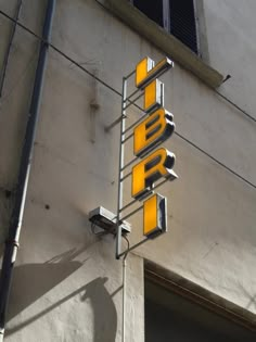 a yellow traffic light hanging from the side of a building next to a street sign