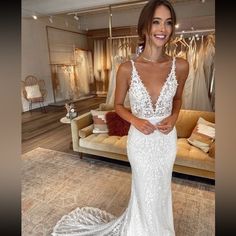 a woman standing in front of a couch wearing a wedding dress with an open back