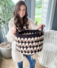 a woman is holding a crocheted bag in her hands and smiling at the camera