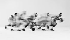 black and white photograph of men playing basketball in motion with blurry image behind them