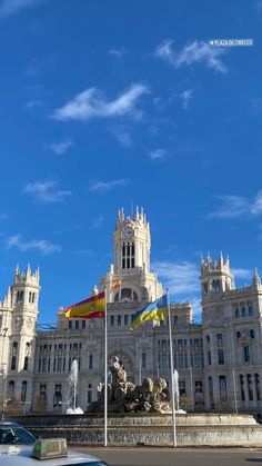 a large building with flags flying in front of it on a clear blue sky day