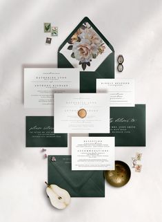 the wedding stationery is set on top of green envelopes, with white and pink flowers