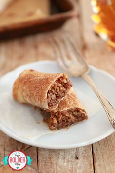 a piece of food on a plate with a fork and glass in the back ground