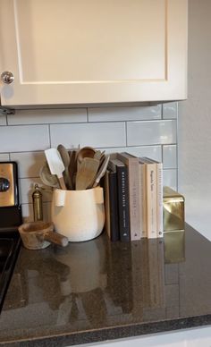 a kitchen counter topped with books and a stove top oven next to a white cabinet