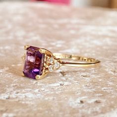 Polished 14KT yellow gold thin band ring with genuine, purple smethyst + surrounding white diamonds. This stunning purple amethyst is the birthstone for February babies + makes a timeless gift! Size 6.75 Can be resized for an additional fee Emerald-cut Amethyst measures: 8mm x 6mm (6) 2 point genuine, round diamonds Stamped 14K Made to order: please allow 5-7 business days prior to shipping Saint Jewelry, Amethyst And Diamond Ring, Round Diamond Ring, Purple Band, Classic Ring, Diamond Sizes, White Diamonds, Purple Amethyst, Gold Plated Sterling Silver