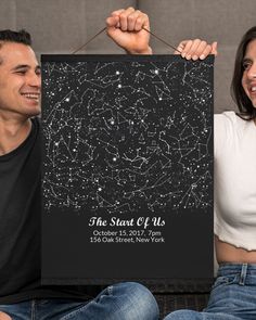 a man and woman sitting on a couch holding up a sign with stars in the sky