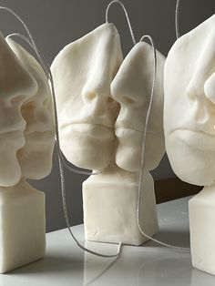 three sculptures made out of white soap on a table with silver strings hanging from them