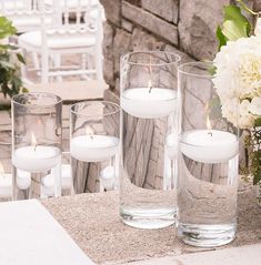 four clear vases filled with white candles