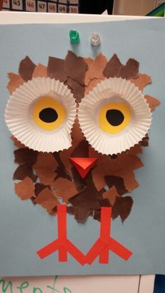 an owl made out of paper on top of a blue board with writing underneath it