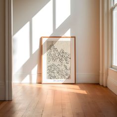 an empty room with a framed drawing on the floor and sunlight coming through the window