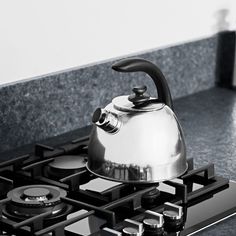 a silver tea kettle sitting on top of a gas stove next to a burner