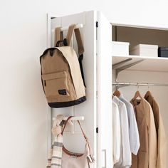 a white closet filled with clothes and bags