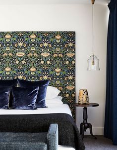 a bed with blue and green wallpaper in a bedroom next to a night stand