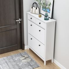 a white dresser sitting next to a door with a purse on it's top