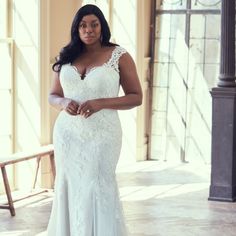 a woman in a white wedding dress posing for the camera with her hands on her hips