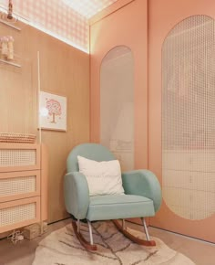 a blue rocking chair sitting on top of a rug in front of a wall with circles