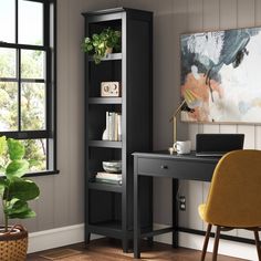 a desk with a laptop on it next to a bookcase and chair in front of a window