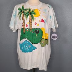 New With Tags Vintage 90s Hand Painted Island Golf T Shirt Top By India Ink Size: One Size Color: White Colorful Hand Painted Island Golf Scene Short Sleeve Shoulder Pads 50% Cotton 50% Polyester Made In U.S.A. Approximate Measurements Taken Laying Flat Chest (Pit To Pit): 23" Shoulder To Hem: 29” Green 90s Style T-shirt For Summer, 90s Style Green T-shirt For Spring, 90s Style White Shirt For Summer, 90s Style Relaxed Fit Summer T-shirt, 90s Style Pre-shrunk T-shirt For Summer, 90s Style Multicolor T-shirt For Summer, Painted Island, Golf T Shirts, India Ink