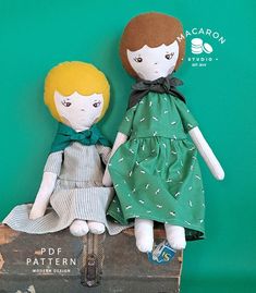 two dolls are sitting on top of an old suitcase, one is green and the other is white