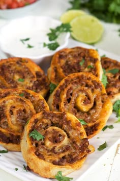 some tasty looking food on a white plate with limes and cilantro