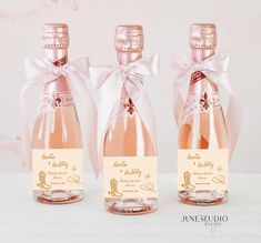 three bottles of pink wine with bows on them