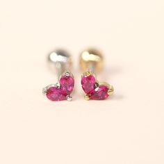 two pink heart shaped earrings sitting on top of each other