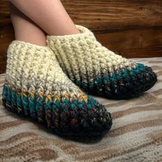 a woman's legs wearing knitted slippers on top of a bed