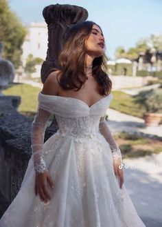 a woman in a white wedding dress standing on a bridge with her hands on her hips