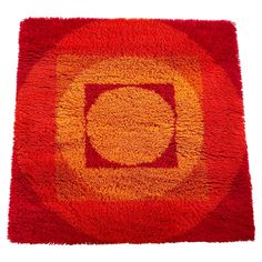 a red and yellow rug with an orange circle in the center on a white background