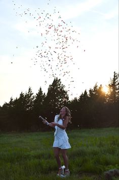 a woman in a white dress holding a tennis racquet while confetti is falling from the sky