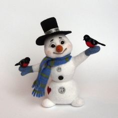 a snowman with two birds on his hand and wearing a top hat, scarf and gloves