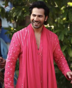 a man in a bright pink outfit is smiling and holding his hands out to the side