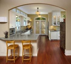 a kitchen with two stools next to an island in the middle of the room