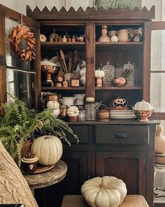 a wooden cabinet filled with lots of pumpkins and other things on top of it