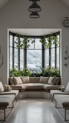 a living room filled with lots of furniture next to a large window covered in potted plants