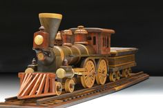 a wooden model of a steam engine train on tracks with wheels and wood trimmings